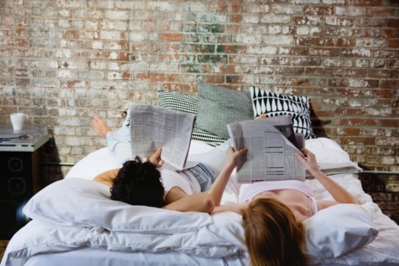 Couple reading newspapers in bed